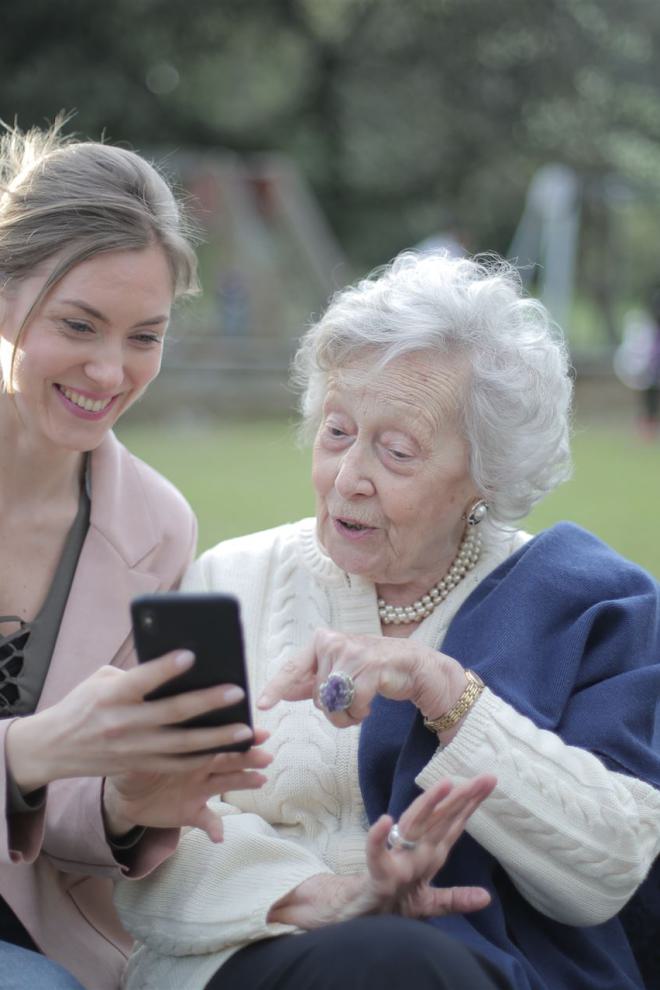 Fröhliche ältere Mutter Und Erwachsene Tochter, Die Smartphone Zusammen Benutzen
